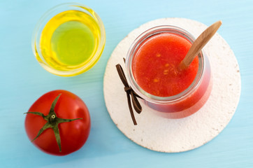 Tomato puree in a glass jar and olive oil for preparing homemade face and hair mask. Ingredients of DIY cosmetics. Top view, copy space.