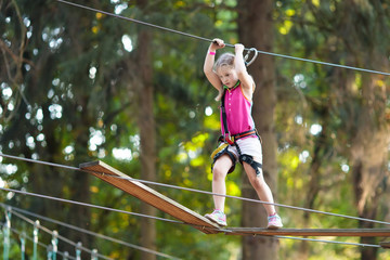 Child in adventure park. Kids climbing rope trail.