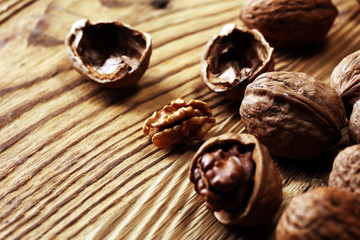Walnut kernels and whole walnuts on rustic old table.