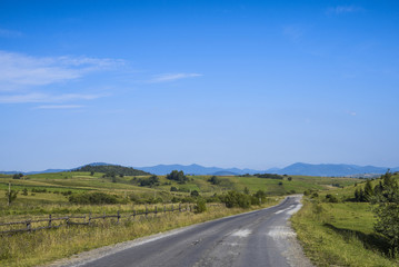 old road through a field in the mountains on a sunny afternoon
