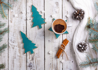 Cup of hot coffee with sugar and cinnamon on old wooden table with spruce branches.