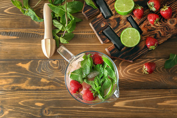 Glass jug with tasty strawberry lemonade on wooden table