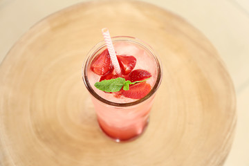 Glass of tasty strawberry lemonade on wooden table