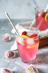 Glass of tasty strawberry lemonade on table