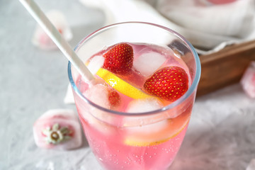 Glass of tasty strawberry lemonade on table, closeup