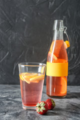 Glass and bottle with tasty strawberry lemonade on table