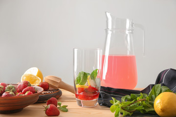 Glass with ingredients for strawberry lemonade on table