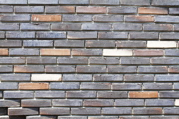 Colorful (grey, beige, black and brown) brick wall as background, texture