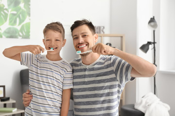 Man and his little son brushing teeth at home