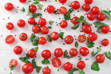 Fresh cherry tomatoes with basil on light background