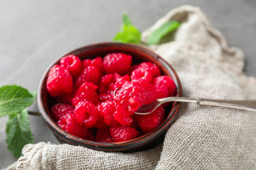 Bowl with delicious raspberries on table