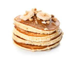 Tasty pancakes with sliced banana and walnuts on white background