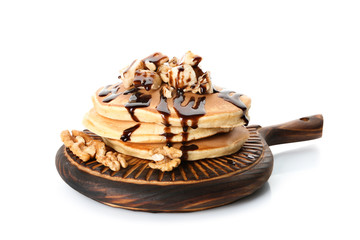 Wooden board with tasty pancakes, sliced banana and walnuts on white background