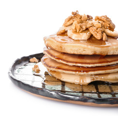 Plate with tasty pancakes, walnuts and sliced banana on white background