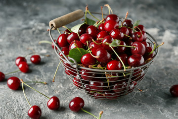 Basket with ripe cherries on grey textured background
