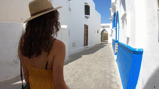4k Video of a Woman with yellow dress and hat walking in a street of a village in Morocco