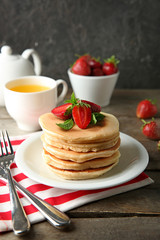 Plate with tasty pancakes and fresh strawberries on wooden table
