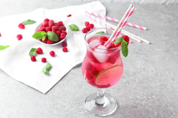 Glass of fresh raspberry mojito on table