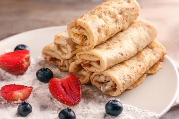 Rolled thin pancakes with berries on plate, closeup
