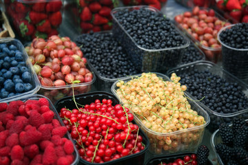 Containers with different ripe berries at market