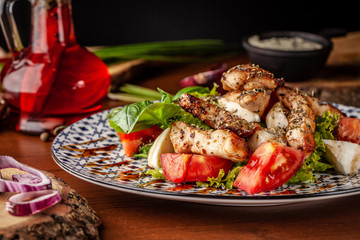 Uzbek traditional cuisine. Salad Zarafshon from roasted chicken fillet, mozzarella cheese, tomatoes, lettuce leaves, olive oil, mustard sauce. Background image. Copy space, selective focus