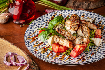 Uzbek traditional cuisine. Salad Zarafshon from roasted chicken fillet, mozzarella cheese, tomatoes, lettuce leaves, olive oil, mustard sauce. Background image. Copy space, selective focus