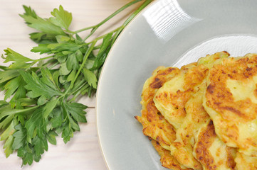 Small pancakes from a zucchini on a plate. White wooden background. Close-up. Macro photography. View from above.
