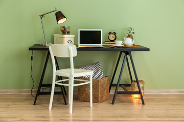Table with laptop near color wall in room