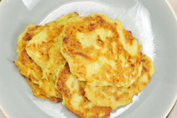 Small pancakes from a zucchini on a plate. The image occupies the entire frame space. Close-up. Macro photography. View from above.