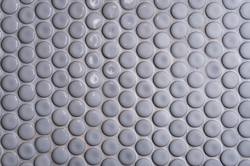 White ceramic tile wall with many small round unique pattern. Top view of bathroom wall tile is a round button tile. Circle white mosaic tile abstract texture background.