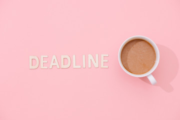 DEADLINE text with a cup of coffee with shadow on pink background.