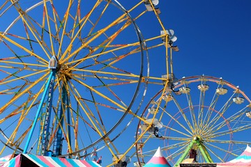 Two colorful ferris wheels with blue sky background