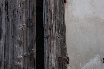 Wallpaper background of an old worn wood window slightly open of a concrete wall house. No people.