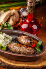 Uzbek traditional oriental cuisine. Lulya kebab from ground beef with pickled onion, salad, cherry tomatoes in a dish of red clay. Background image. Copy space, selective focus