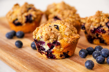 freshly baked blueberry muffins with an oat crumble topping on a natural wooden board - obrazy, fototapety, plakaty