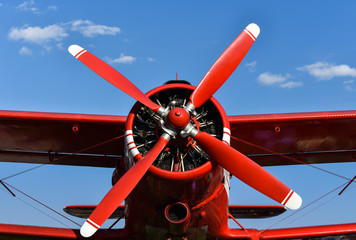 red biplane with propeller on background sky