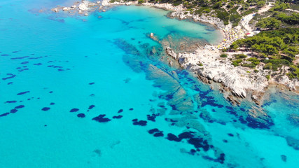 Aerial view of beautiful sandy and rocky Orange beach, people sunbathing and swimming. Amazing and famous Portokali beach on Sithonia near Sarti, Greece