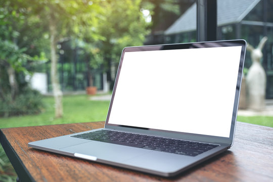Mockup image of laptop with blank white desktop screen on vintage wooden table with nature background