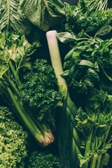 Fotobehang top view of green vegetables and herbs on table © LIGHTFIELD STUDIOS