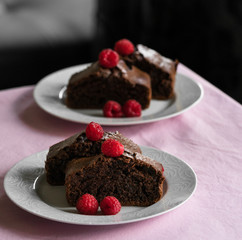 dessert of moist chocolate cake on pink table cloth, dark background