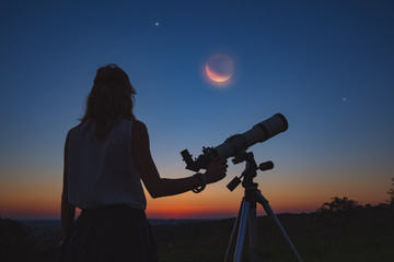 Fototapeta premium Girl looking at lunar eclipse through a telescope. My astronomy work.