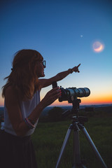 Naklejka premium Girl looking at lunar eclipse through a telescope. My astronomy work.