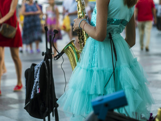 back view of girl play saxophone in the street