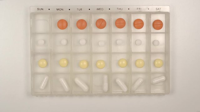 TOP VIEW: Senior male hand takes a pill from a plastic pill organizer