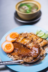Rice with BBQ Pork and Crispy Pork on the blue dish on the table. This is street food menu in Bangkok.