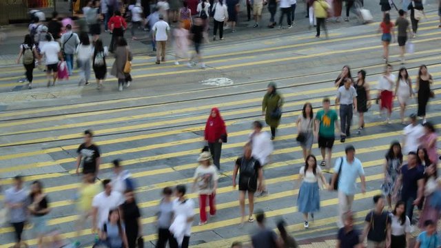 Crowd of people walking crossing street at a busy intersection in Hong Kong,