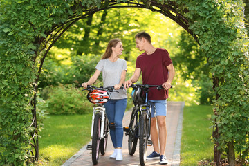 Young couple with bicycles walking in park