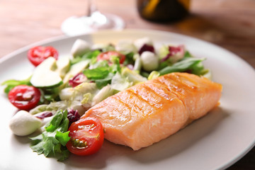 Tasty grilled fish and fresh salad on plate, closeup