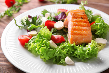 Tasty grilled fish and fresh salad on plate, closeup