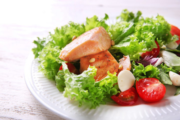 Plate with tasty grilled fish and fresh salad on table, closeup